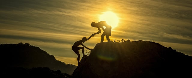 Boy lending a helping hand to a friend up a hill